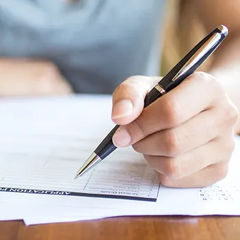 Close up image of a person writing on a form