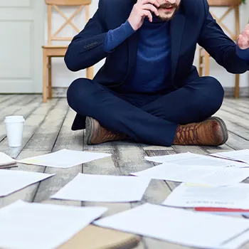 A busy man finding a certain document on the floor