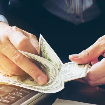 A business person counting money on a table