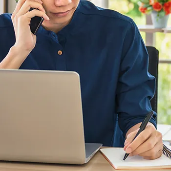 A person writing while calling someone