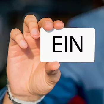 A man in blue attire holding a white plain card