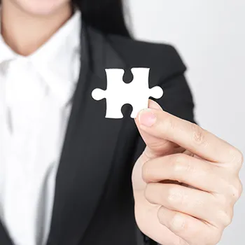 A woman in business attire holding a piece of puzzle