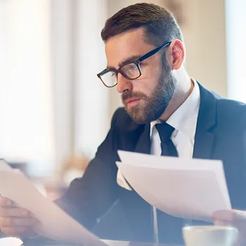 Venture Smarter | What is an LLC Registered Agent? (The Complete Guide) A bearded man in suit reading files