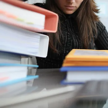 Stack of files on table in front of woman