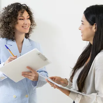 Two smiling woman holding clipboards