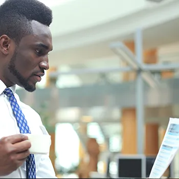 Man reading a document while drinking coffee