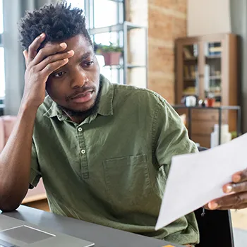 Person holding his head while reading papeworks