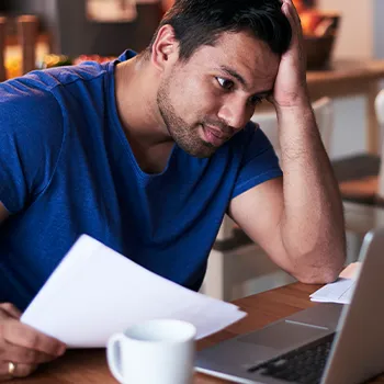 Man holding a document list while looking at computer