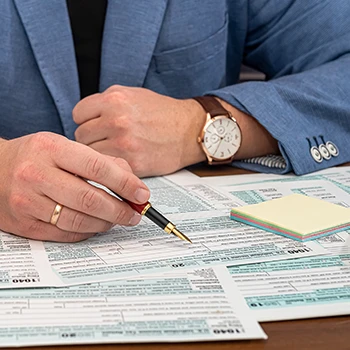 Businessman filing business tax forms with sticky notes on his desktop