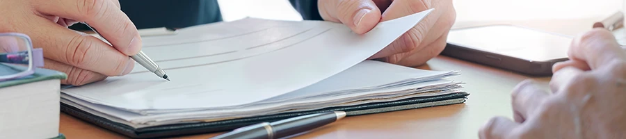 Close up image of man writing on a stack of paper about dissolution of an LLC in South Carolina