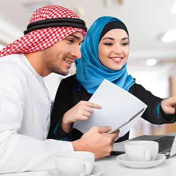 Arab couple looking at a laptop screen while holding a file