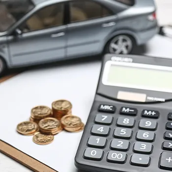 Miniature car with coins and calculator expenses concept