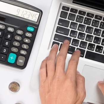 Top view of laptop and a calculator, calculating cost of an LLC in Tennessee