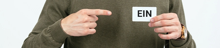 Man pointing at his white card with EIN initials