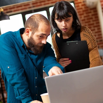 Pointing at the laptop to mentor work mate