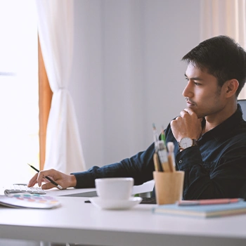 A man in front of his computer thinking thoroughly