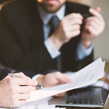 Businessman watching co worker sign and check a file