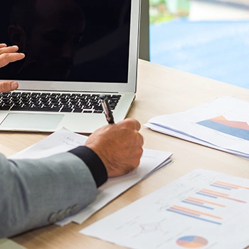 Different documents lying on the table while person is working on laptop