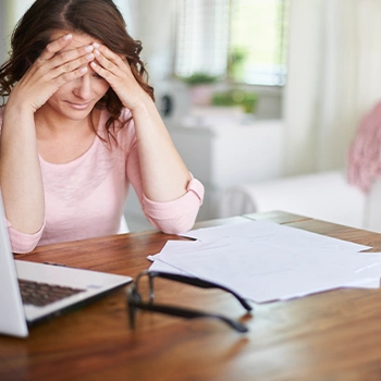 A woman holding her head from stress caused by too much paper works