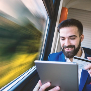 An LLC owner holding a business credit card while working remotely on a train