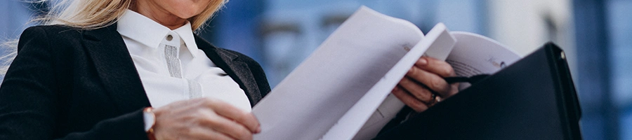 A businesswoman in formal attire holding a large file of documents