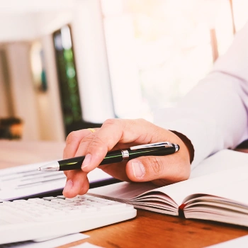 A man using a calculator with a book