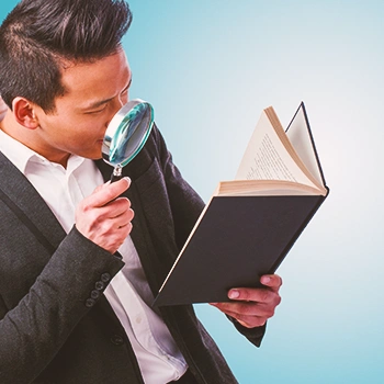 An office man looking in a book with a magnifying glass