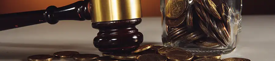 A lawyers gavel with jar full of coins