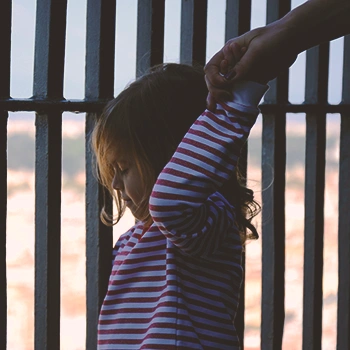 A child in front of a metal fence