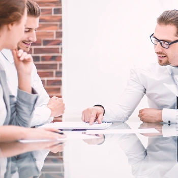 Three office persons discussing about LLC formation in Vermont at a table