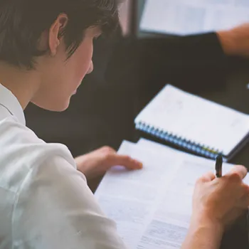 A person writing on paperwork