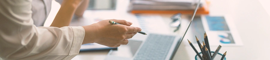 An office worker pointing at a laptop with a pen