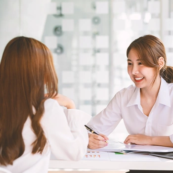 Two coworkers sitting in front of each other smiling