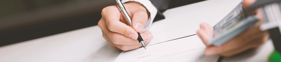 A person holding money while signing a paper