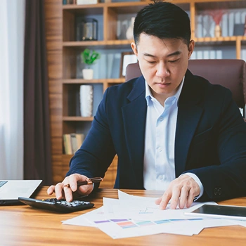 A businessman calculating things on a piece of paper with a calculator