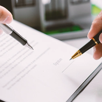 Two person pointing at a contract with their pens