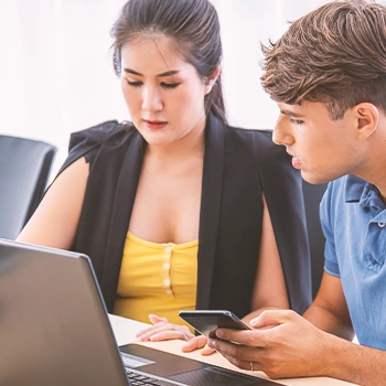 Two coworkers looking at a laptop