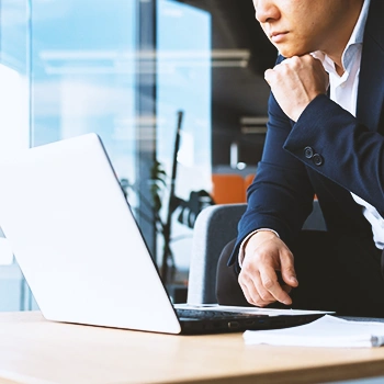 A business man thinking in front of a laptop