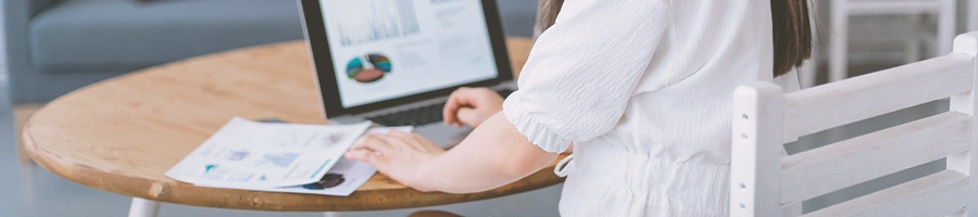 A person with paperwork and a laptop on the desk