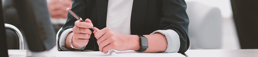 A business person holding a pen while sitting