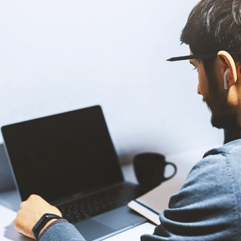 A person using a black laptop with a black mug beside to look up for an llc in louisiana