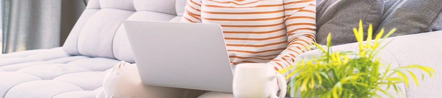 A person sitting on a couch while using a laptop