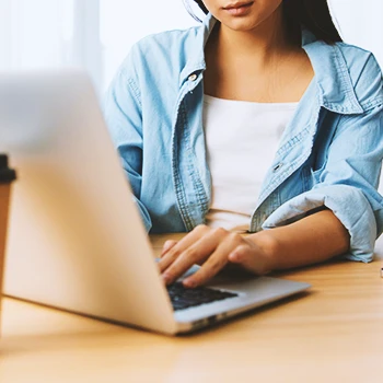 A woman using a white laptop on a table