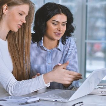 Two coworkers discussing in front of a laptop