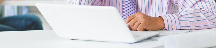 An office person using a white laptop on a white table