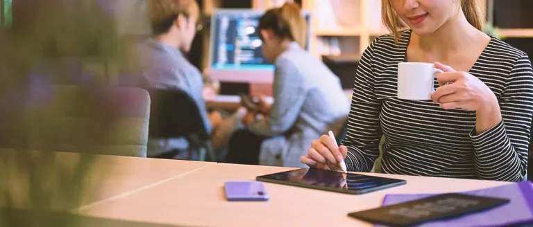 A Virginia registered agent drinking coffee and writing on her tablet in an office