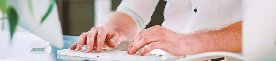 A person typing on a white keyboard in an office