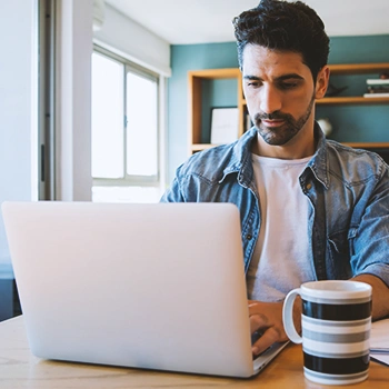 A person working on a laptop with coffee on the side