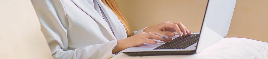 A person using her laptop that is on a pillow