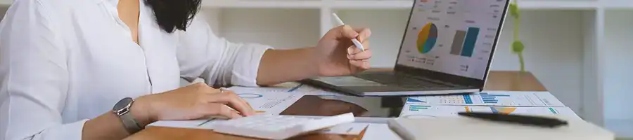 An office worker doing paperwork while using a laptop